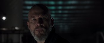 Movie still from “Iron Man” (2008), directed by Jon Favreau – A man with a shaved head and a goatee is looking at the camera; Close Up shot, Low angle