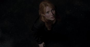 Movie still from “Iron Man” (2008), directed by Jon Favreau – A red haired woman holding a gun in a dark room; Close Up shot, Overhead angle