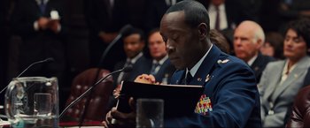 Movie still from “Iron Man 2” (2010), directed by Jon Favreau – A man in military uniform reading a book; Close Up shot, Over the shoulder angle