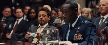 Movie still from “Iron Man 2” (2010), directed by Jon Favreau – Two men sitting at a table in front of microphones; Close Up shot, Over the shoulder angle