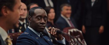 Movie still from “Iron Man 2” (2010), directed by Jon Favreau – A person sitting in front of other people; Close Up shot, Over the shoulder angle