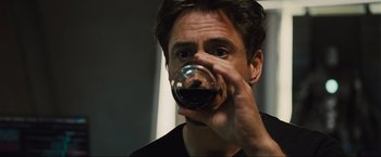 Movie still from “Iron Man 2” (2010), directed by Jon Favreau – A person holding a glass of red wine; Close Up shot, Over the shoulder angle