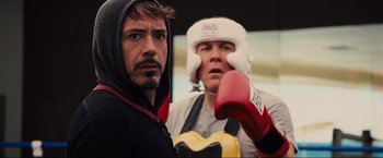 Movie still from “Iron Man 2” (2010), directed by Jon Favreau – Two men are posing for a picture while wearing boxing gloves; Close Up shot, Over the shoulder angle