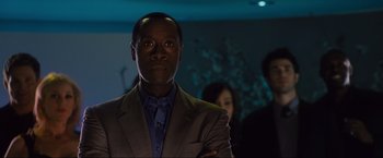 Movie still from “Iron Man 2” (2010), directed by Jon Favreau – A man in a gray suit and a blue shirt; Close Up shot, Low angle