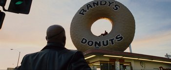 Movie still from “Iron Man 2” (2010), directed by Jon Favreau – A man standing in front of a giant doughnut; Extreme Wide shot, Over the shoulder angle