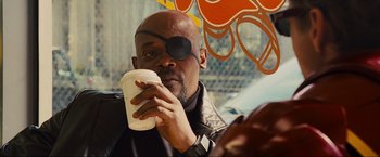 Movie still from “Iron Man 2” (2010), directed by Jon Favreau – A man wearing a eye patch drinking a cup of coffee; Close Up shot, Over the shoulder angle