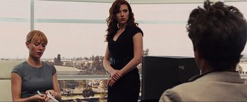 Movie still from “Iron Man 2” (2010), directed by Jon Favreau – A woman in a black dress standing in front of a window; Medium shot, Over the shoulder angle