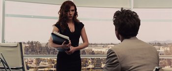 Movie still from “Iron Man 2” (2010), directed by Jon Favreau – A woman in a black dress is holding a folder; Medium shot, Over the shoulder angle