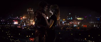 Movie still from “Iron Man 2” (2010), directed by Jon Favreau – A man and a woman standing next to each other in front of a city skyline at night; Medium shot, Low angle