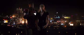 Movie still from “Iron Man 2” (2010), directed by Jon Favreau – A man and a woman standing next to each other in front of a city skyline at night; Medium shot, Low angle