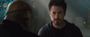 Movie still from “Iron Man 2” (2010), directed by Jon Favreau – A person with a microphone in a room; Close Up shot, Over the shoulder angle