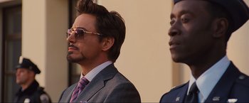 Movie still from “Iron Man 2” (2010), directed by Jon Favreau – A man in a suit and tie standing next to another man in a suit and tie; Close Up shot, Low angle