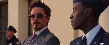 Movie still from “Iron Man 2” (2010), directed by Jon Favreau – A man in a suit and tie standing next to another man in a suit and tie; Close Up shot, Over the shoulder angle