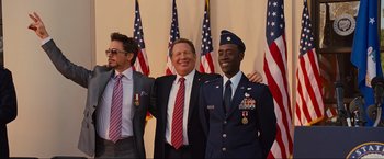 Movie still from “Iron Man 2” (2010), directed by Jon Favreau – A group of men standing in front of american flags; Medium shot, Low angle