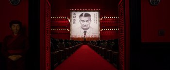 Movie still from “Isle of Dogs” (2018), directed by Wes Anderson – An auditorium with rows of seats and a large poster of kobayashi; Wide shot, Low angle