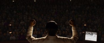 Movie still from “Isle of Dogs” (2018), directed by Wes Anderson – A man with his hands raised in front of a crowd; Extreme Wide shot, High angle