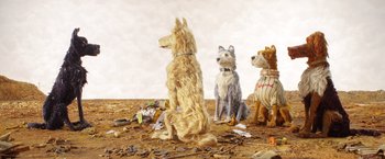 Movie still from “Isle of Dogs” (2018), directed by Wes Anderson – A group of dogs sitting next to each other on the ground; Wide shot, Low angle
