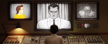 Movie still from “Isle of Dogs” (2018), directed by Wes Anderson – A man is sitting in front of a television; Medium shot, Low angle