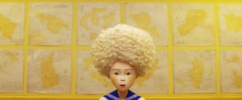 Movie still from “Isle of Dogs” (2018), directed by Wes Anderson – A doll wearing a wig; Close Up shot, Overhead angle