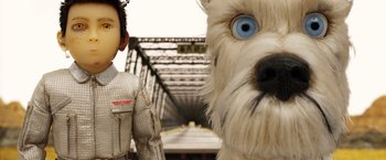 Movie still from “Isle of Dogs” (2018), directed by Wes Anderson – A toy dog and a toy man in a train station; Close Up shot, Low angle