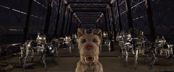 Movie still from “Isle of Dogs” (2018), directed by Wes Anderson – A dog is standing in front of a group of robots; Wide shot, Low angle