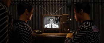 Movie still from “Isle of Dogs” (2018), directed by Wes Anderson – An old tv with a man on the screen; Medium shot, Over the shoulder angle