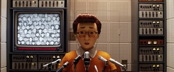 Movie still from “Isle of Dogs” (2018), directed by Wes Anderson – A person with a microphone in front of microphones in a room; Medium shot, Low angle