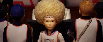 Movie still from “Isle of Dogs” (2018), directed by Wes Anderson – A doll with a large afro wig on it's head; Close Up shot, Low angle
