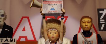 Movie still from “Isle of Dogs” (2018), directed by Wes Anderson – A person holding up a sign that says " daily manifesto "; Close Up shot, Low angle