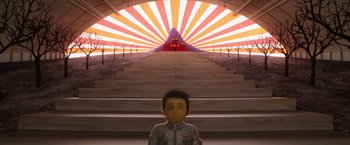 Movie still from “Isle of Dogs” (2018), directed by Wes Anderson – A doll in front of an image of a staircase; Extreme Wide shot, Low angle