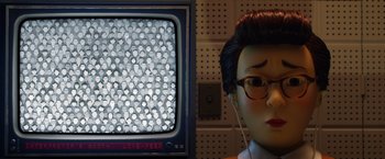 Movie still from “Isle of Dogs” (2018), directed by Wes Anderson – A doll wearing glasses and headphones next to a television screen; Extreme Close Up shot, High angle