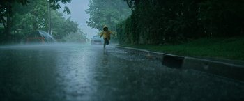 Movie still from “It” (2017), directed by Andy Muschietti – A person riding a bike down a rain covered street; Extreme Wide shot, Low angle