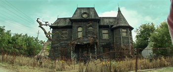 Movie still from “It” (2017), directed by Andy Muschietti – An old house with a clock on the front of it; Wide shot, Low angle