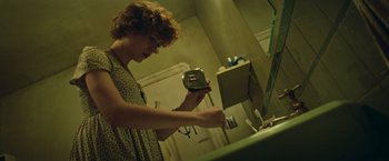 Movie still from “It” (2017), directed by Andy Muschietti – A woman in a bathroom looking at a mirror and brushing her teeth; Medium shot, Low angle