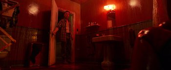 Movie still from “It” (2017), directed by Andy Muschietti – A man standing in a bathroom next to a sink; Wide shot, Low angle