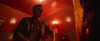 Movie still from “It” (2017), directed by Andy Muschietti – A man standing in a room with a red ceiling; Medium shot, Low angle
