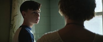 Movie still from “It” (2017), directed by Andy Muschietti – A boy and a woman are looking at each other in a bathroom; Close Up shot, Over the shoulder angle