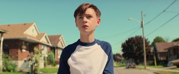 Movie still from “It” (2017), directed by Andy Muschietti – A young boy standing on the side of the street; Close Up shot, Low angle