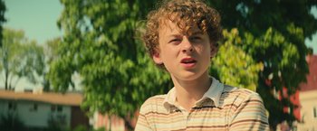 Movie still from “It” (2017), directed by Andy Muschietti – A young man with curly hair is standing outside; Close Up shot, Low angle