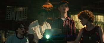 Movie still from “It” (2017), directed by Andy Muschietti – Two young men standing next to each other in front of a projector; Medium shot, Low angle