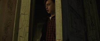 Movie still from “It” (2017), directed by Andy Muschietti – A young man standing in front of an open door; Medium shot, Low angle