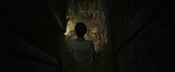 Movie still from “It” (2017), directed by Andy Muschietti – A person sitting in a dark room looking up; Wide shot, Overhead angle