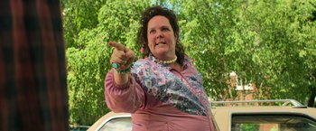 Movie still from “It” (2017), directed by Andy Muschietti – A woman in a pink shirt is pointing to the side; Medium shot, Low angle