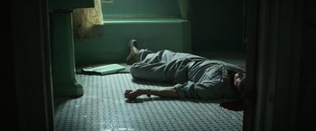 Movie still from “It” (2017), directed by Andy Muschietti – A man laying on the ground in a bathroom; Wide shot, High angle