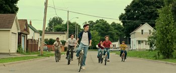 Movie still from “It” (2017), directed by Andy Muschietti – A group of people riding bikes down a street; Wide shot, High angle