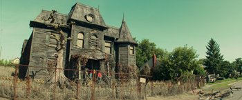 Movie still from “It” (2017), directed by Andy Muschietti – Two people standing in front of an abandoned house; Wide shot, Low angle