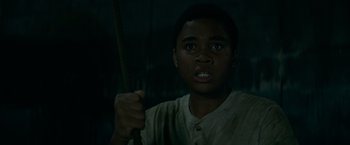 Movie still from “It” (2017), directed by Andy Muschietti – A young man holding a wooden stick in a dark room; Close Up shot, Low angle