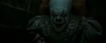 Movie still from “It” (2017), directed by Andy Muschietti – A clown's face with yellow eyes; Close Up shot, Over the shoulder angle