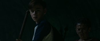 Movie still from “It” (2017), directed by Andy Muschietti – A young boy is standing in a dark room; Medium shot, High angle