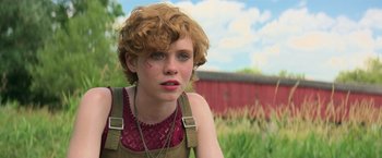 Movie still from “It” (2017), directed by Andy Muschietti – A young woman with red curly hair wearing a red shirt; Close Up shot, Over the shoulder angle